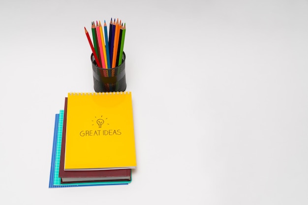 Livre et bloc-notes avec des crayons dans un panier sur fond blanc, isolé. retour à l'école. Bonnes idées