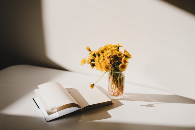 un livre et un bouquet de pissenlits jaunes