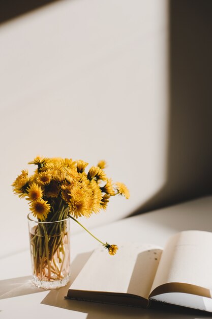 un livre et un bouquet de pissenlits jaunes