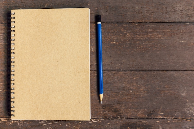 livre brun et un crayon sur fond de table en bois avec espace