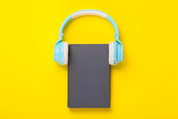 Livre et casque sur fond jaune.