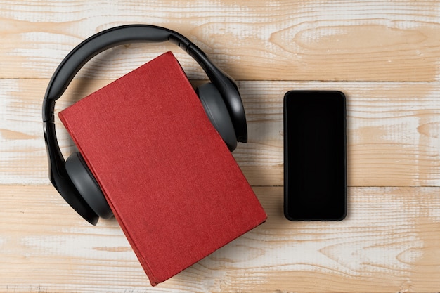 Livre, casque et téléphone sur fond en bois. Concept de livre audio. Vue de dessus, espace copie