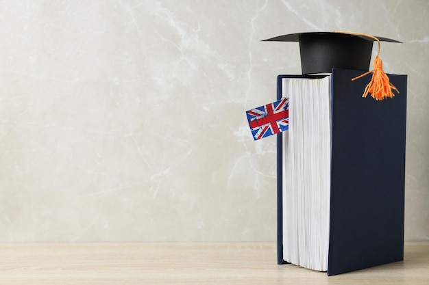 Photo un livre avec une casquette de graduation et le drapeau de la grande-bretagne