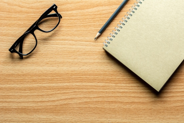 Livre, crayon et lunettes sur un bureau en bois