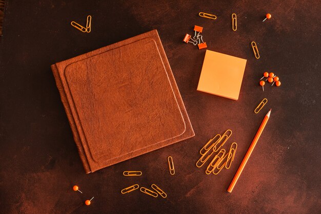 Le livre, le crayon, les trombones et les feuilles de marques se trouvent sur un bureau