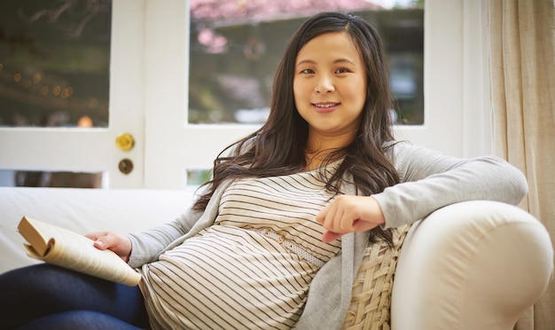 Ce livre est une lecture incontournable pour toute future maman Portrait d'une femme enceinte lisant un livre à la maison