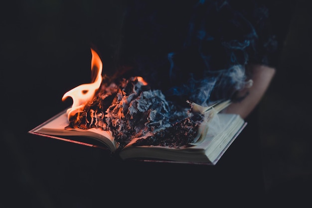 Un livre en feu sur un fond noir.