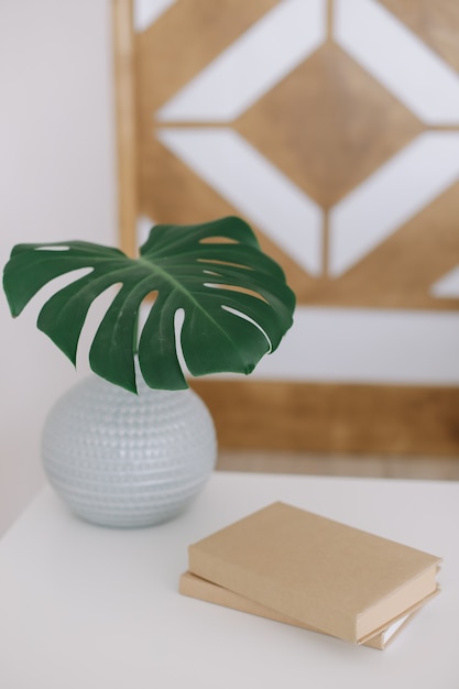 Un livre et une feuille de palmier dans un vase sur la table