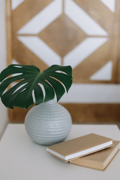 Un livre et une feuille de palmier dans un vase sur la table