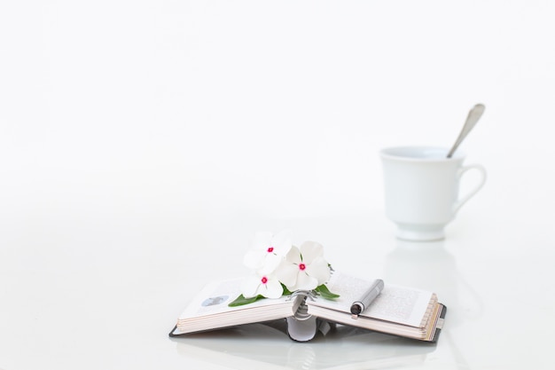 Livre avec des fowers et une tasse de café sur une table en marbre blanc