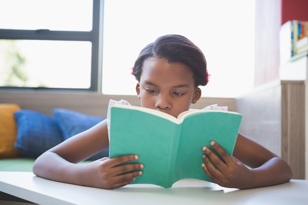 Photo livre de lecture d'écolière dans la bibliothèque