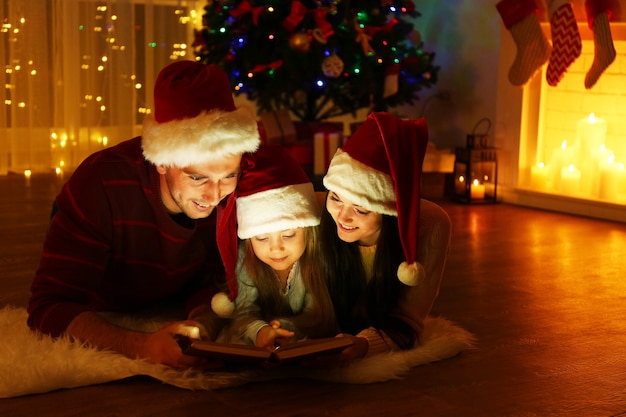 Livre de lecture de famille heureuse dans le salon décoré pour Noël