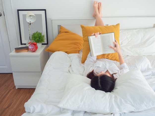 Livre de lecture de femme asiatique sur le lit le matin