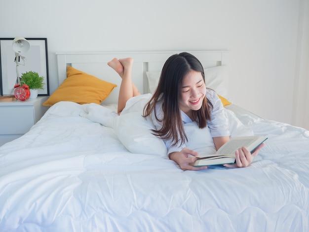 Livre de lecture de femme asiatique sur le lit le matin