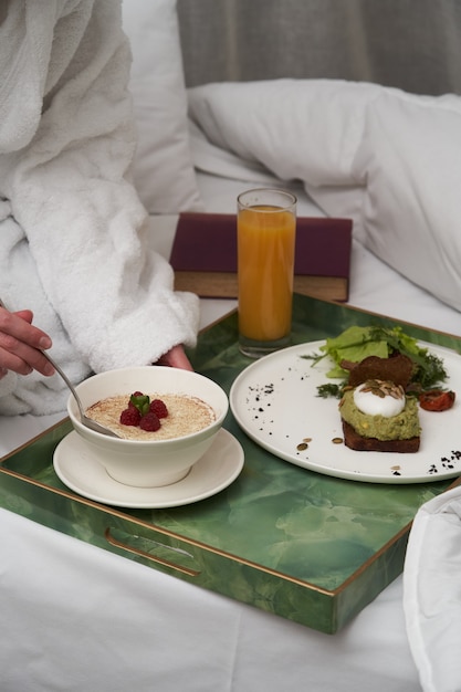 Photo livre de lecture de femme tout en prenant son petit déjeuner au lit. femme, dans, peignoir, petit déjeuner, dans, lit hôtel, gros plan