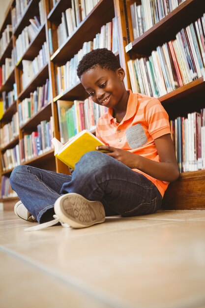 Livre de lecture garçon mignon dans la bibliothèque