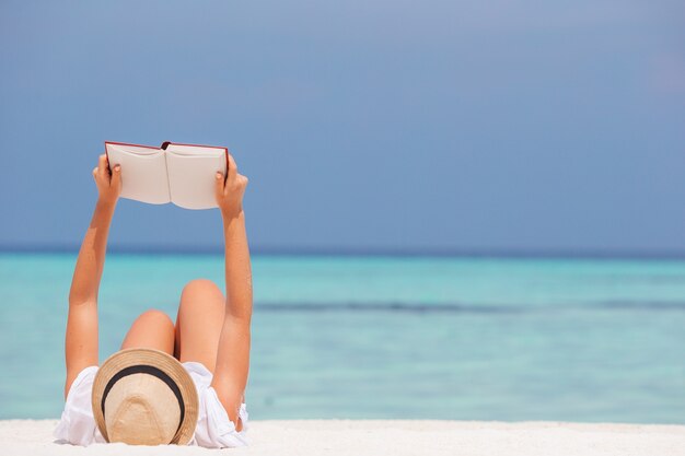 Livre de lecture de jeune femme pendant la plage blanche tropicale