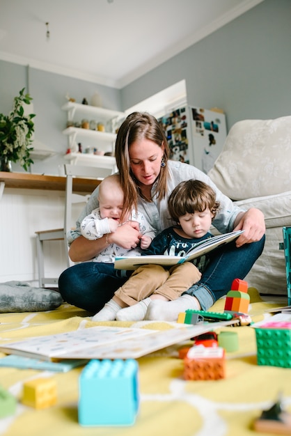 Livre de lecture mère avec enfants assis sur le sol