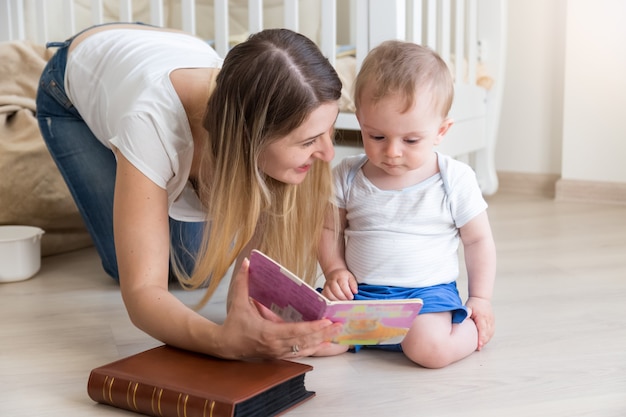 Livre de lecture de mère à son petit garçon de 10 mois sur marbre au salon