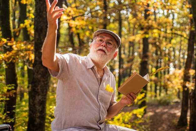 Livre de lecture Passe-temps et loisirs Grand-père dans la nature Uni avec la nature Week-end dans la nature Vacances et détente Concept de retraite Personnes âgées Homme mûr barbe blanche forêt Auteur talentueux