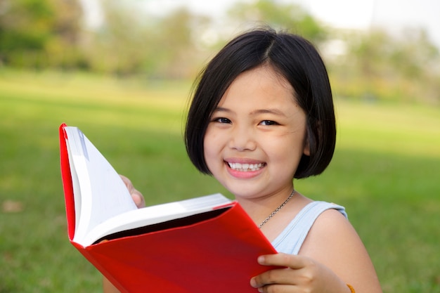 Livre de lecture de petite fille asiatique dans le parc