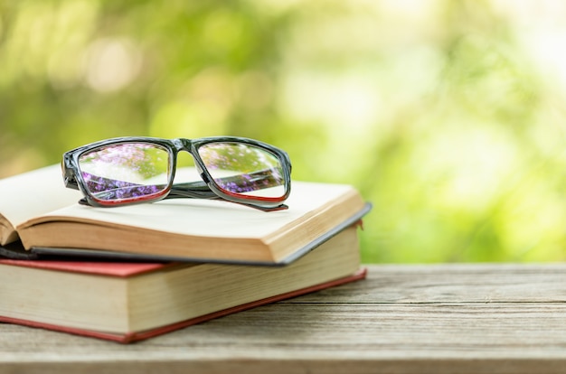 Livre et lunettes sur table en bois avec nature verte abstraite flou Concept de lecture et d'éducation