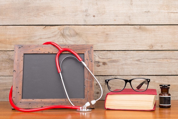 Livre de lunettes tableau blanc vierge et stéthoscope sur fond de bois