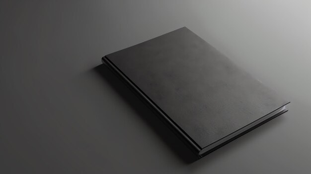 Photo un livre noir élégant est posé sur une surface grise solide. le livre est fermé et la colonne vertébrale est tournée vers le spectateur.