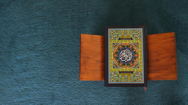 Un livre avec le nom d'Allah dessus est assis sur un tapis bleu.