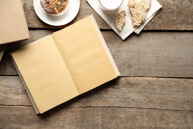 Livre ouvert et collation sur fond de table en bois