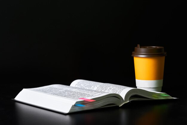 Livre ouvert avec des signets et une tasse de café sur fond sombre