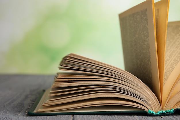 Livre ouvert sur une table en bois gris sur fond vert flou libre