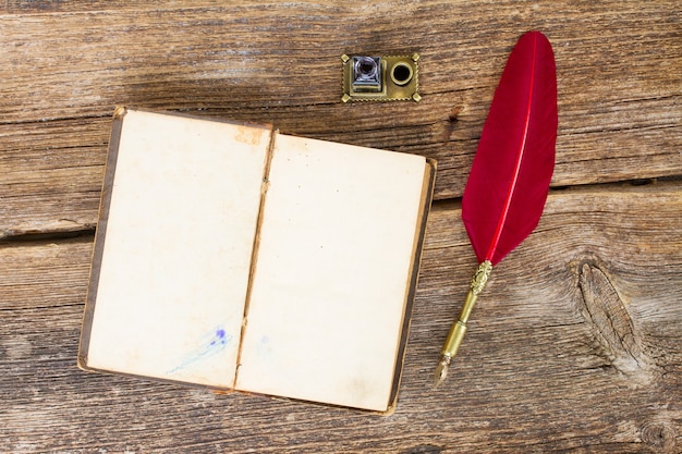 Livre ouvert vierge vintage avec plume rouge, vue de dessus