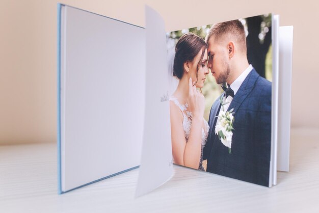 Livre photo ouvert avec photo wrdding d'un beau couple sur une table en bois blanc