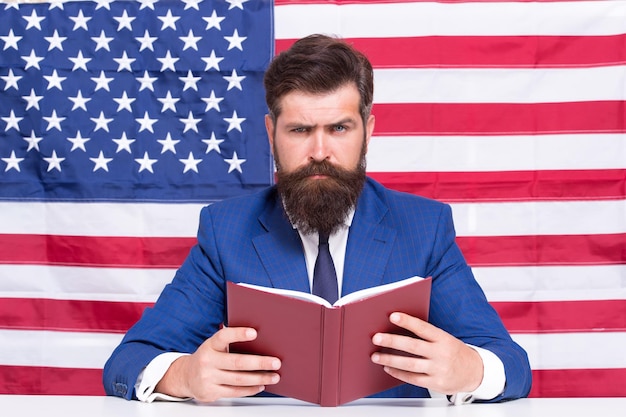 Photo livre pour maîtriser l'anglais américain homme barbu lire un livre sur fond de drapeau américain livre de lecture vocabulaire et grammaire connaissances et informations bibliothèque et bibliotheca livre des enseignants