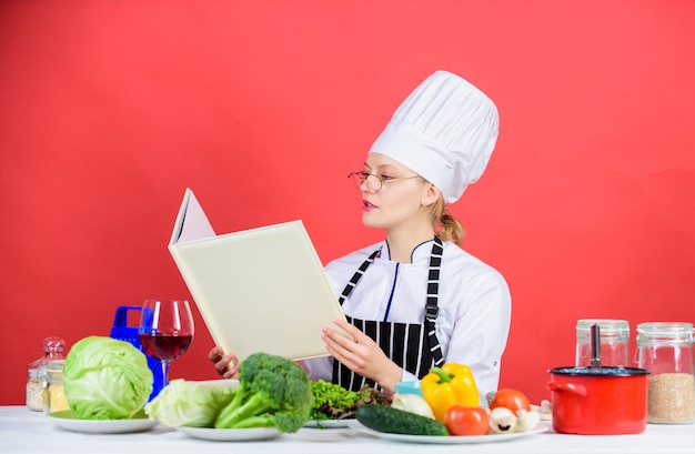 Livre qui vous donnera vraiment faim Dame cuisinière à la recherche d'une recette dans un livre de cuisine Jolie femme lisant un livre de cuisine dans la cuisine Femme de ménage apprenant de nouveaux plats à partir d'un livre de recettes