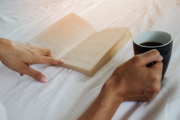 Livre et une tasse de café sur le lit