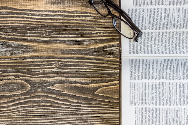 Un livre vide ouvert et des lunettes sont sur une surface en bois