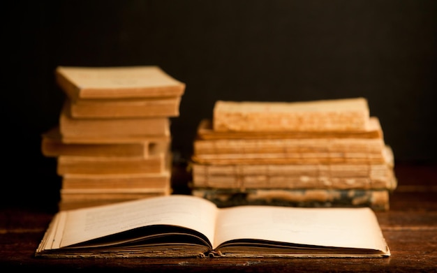 livre vintage ouvert sur un bureau en bois avec des livres