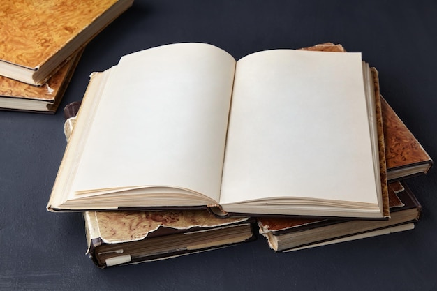Un livre vintage ouvert dans une super couverture se trouve sur une pile de vieux livres délabrés sur une table en béton sombre Espace de copie maquette