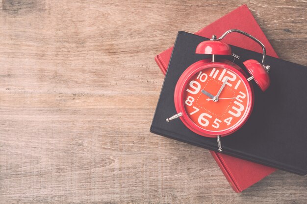 Livre de vue de dessus et horloge rouge sur fond de planche de bois. Temps pour lire le concept