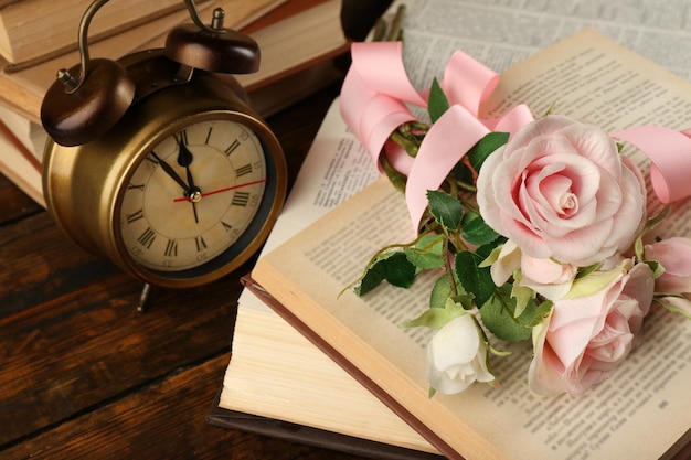 Livres avec fleurs et horloge sur fond de bois