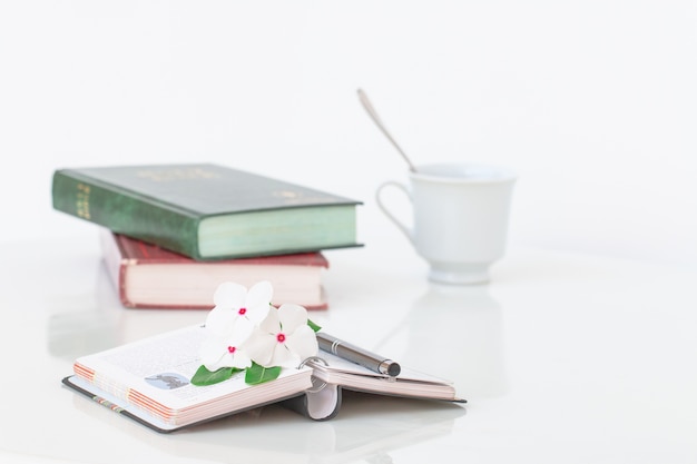 Livres avec des fowers et une tasse de café sur une table en marbre blanc