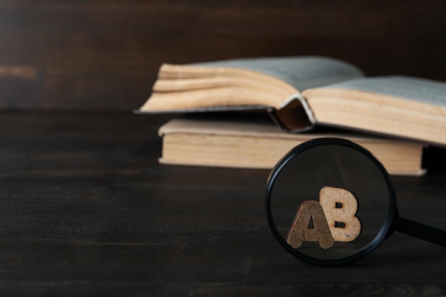 Livres et lettres en loupe sur fond en bois, espace pour le texte