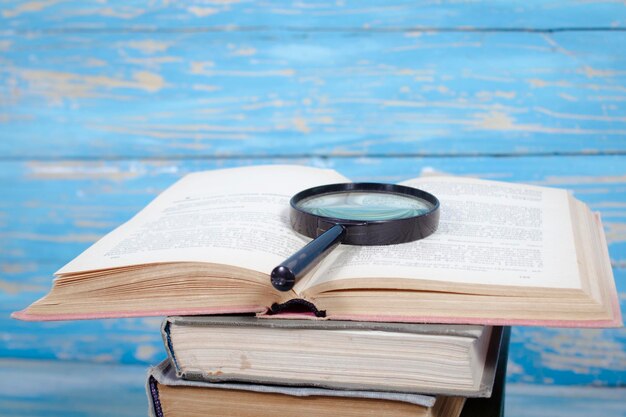 Livres et loupe sur une table en bois bleue