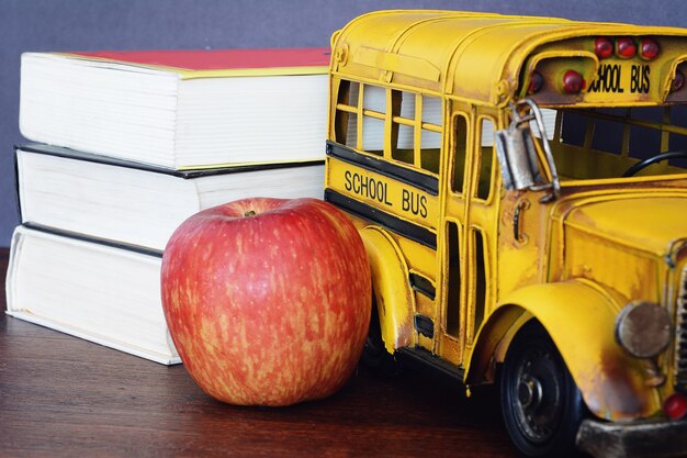 Livres, pomme, crayons et bus étudiant