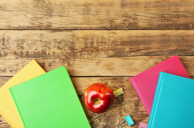 Livres et pomme sur fond de bois