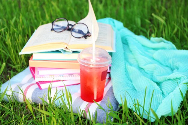 Photo livres verres et boisson sur l'herbe libre