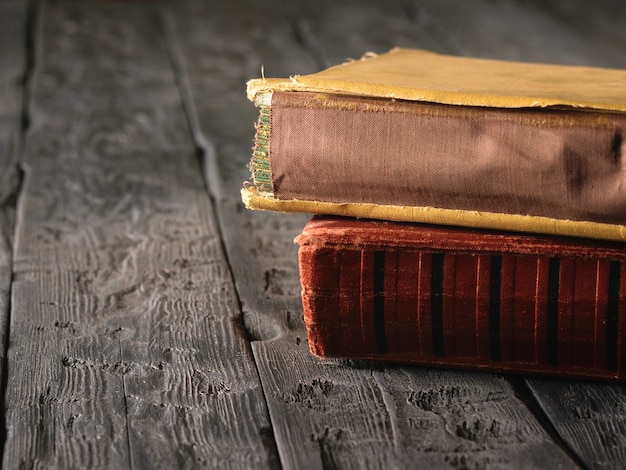 Livres vintage rouges et jaunes sur une table en bois sombre. Littérature du passé.