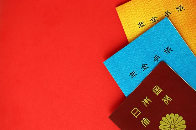 Des livrets d'assurance-pension japonais sur la table avec le passeport Livre de retraite bleu et orange
